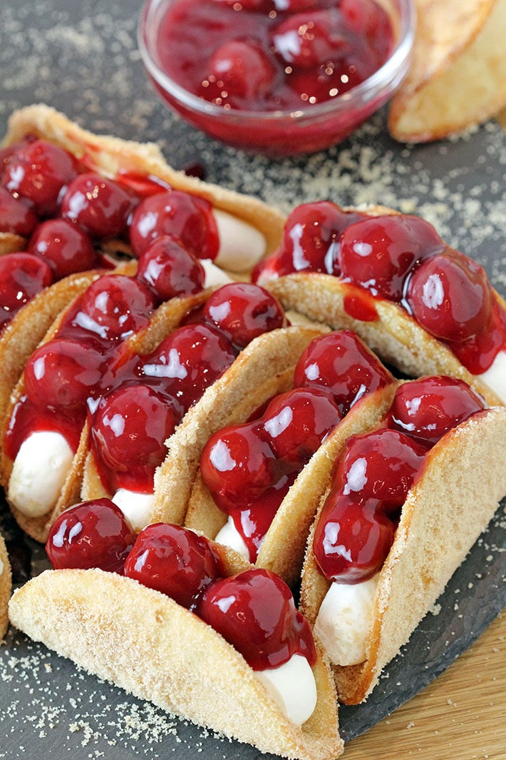 Cherry Cheesecake Tacos – these mini dessert tacos made with sweet ingredients and shaped like traditional tacos are so much fun to prepare, they look classy and are very delicious. You will love crunchy tortilla shells covered with sugar and cinnamon, filled with creamy no bake cheesecake filling that are topped with cherry pie filling.