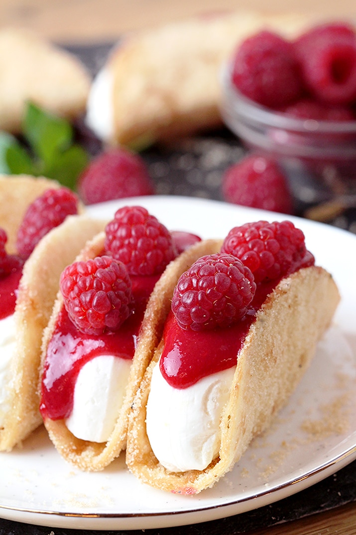 Raspberry Cheesecake Tacos – crunchy tortilla shells, creamy cheesecake filling, topped with raspberry sauce and fresh raspberries on top make this amazing dessert. These incredible bites are perfect for holidays, parties and other events. 
