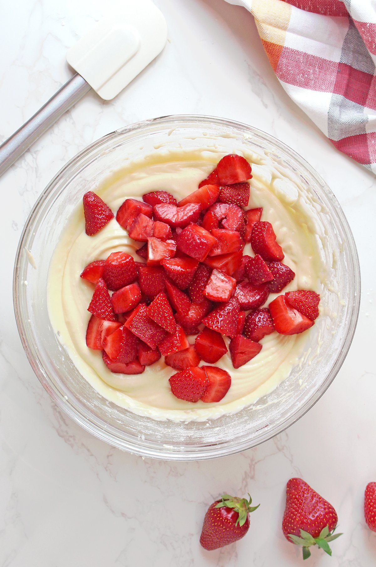 Step 5: Fold in Strawberries
Gently fold most strawberries into the batter.