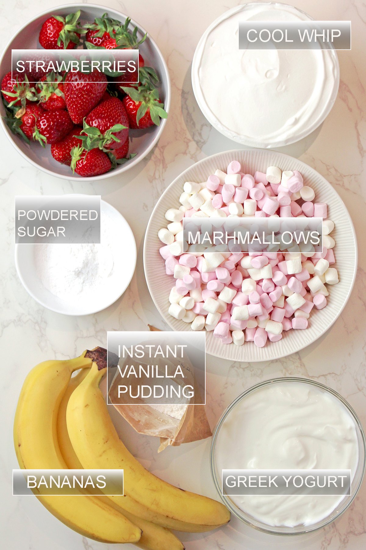 Ingredients for this fluff salad including Greek yogurt, vanilla pudding mix, Cool Whip, marshmallows, fresh strawberries and bananas.