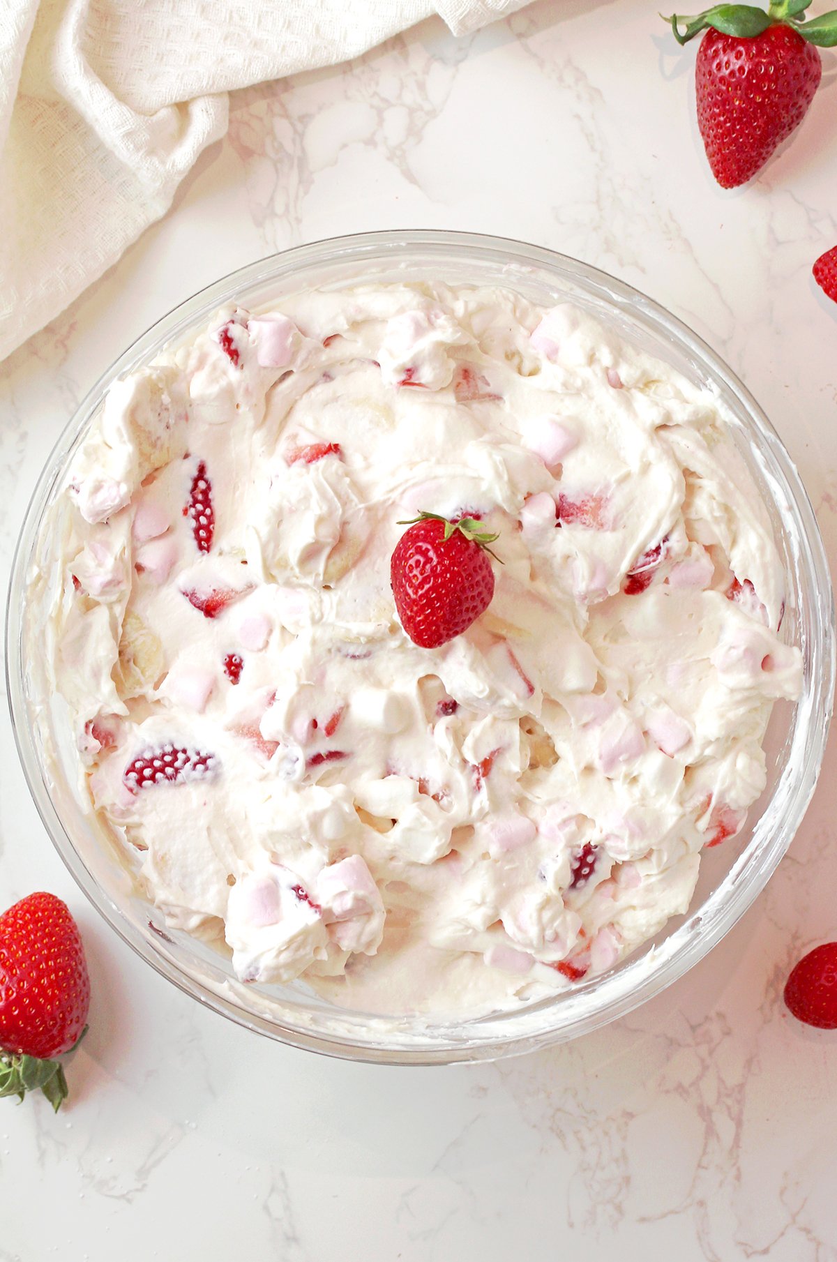 Easy strawberry banana fluff salad in a bowl topped with fresh strawberries, bananas, and mini marshmallows, creamy no bake dessert.
