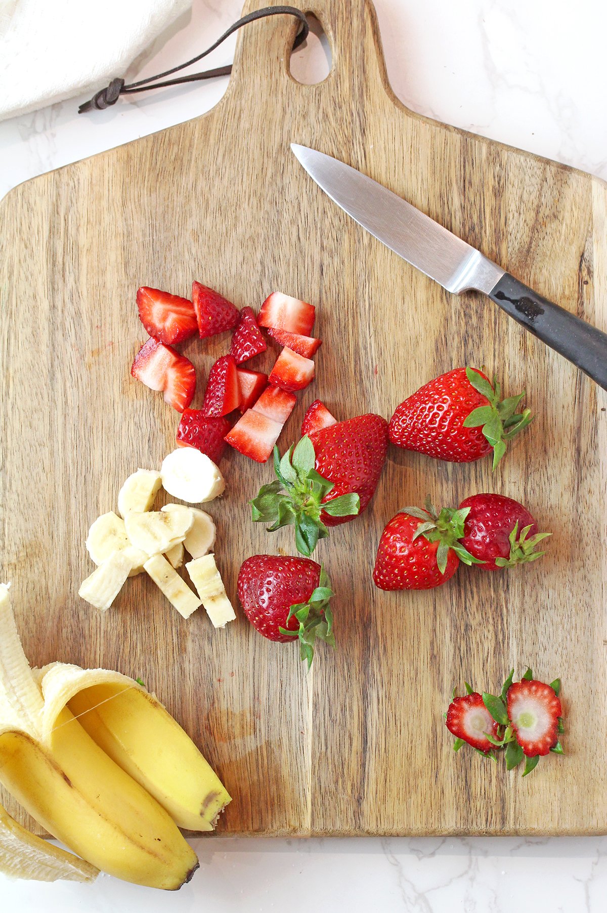 Slicing fresh strawberries and bananas for easy fluff salad recipe.