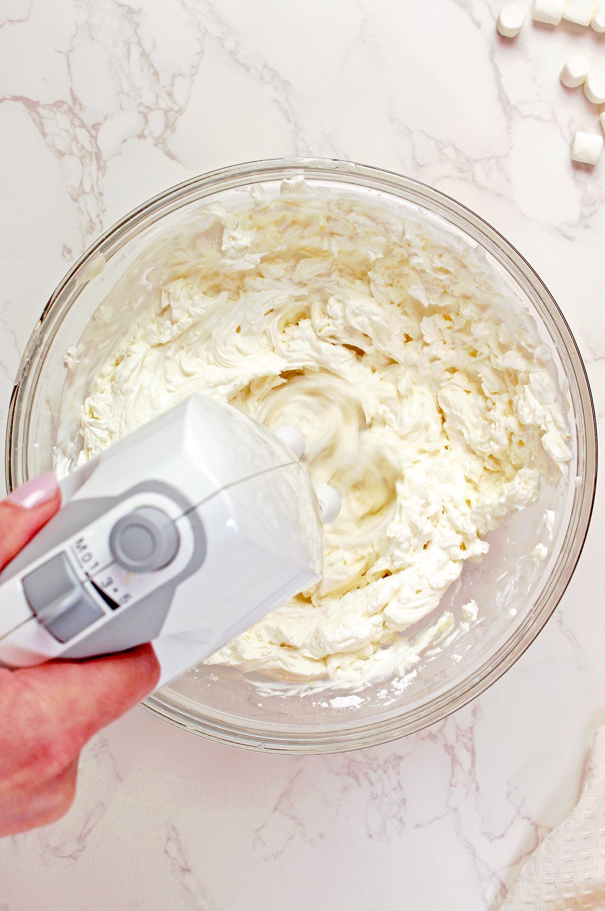 Beating cream cheese, Greek yogurt, powdered sugar, and vanilla for Creamsicle Orange Cheesecake Fluff Salad.