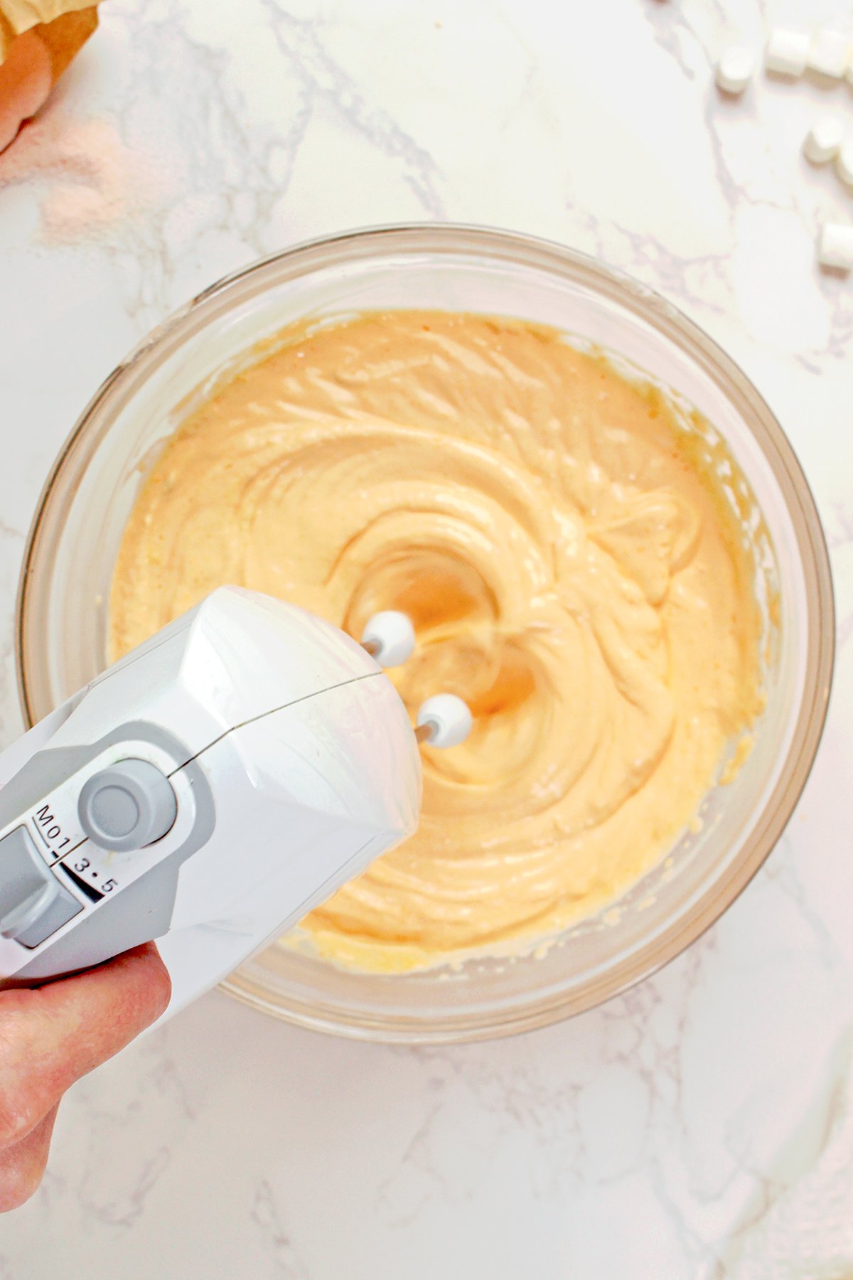 Mixing orange juice and orange Jello into the cream cheese mixture.