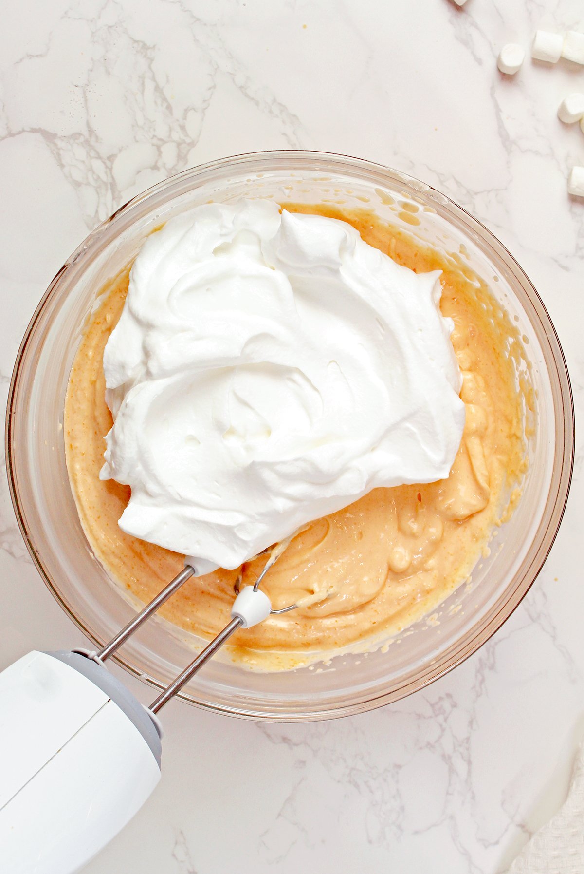 Beating Cool Whip into the orange cheesecake mixture until light and fluffy.