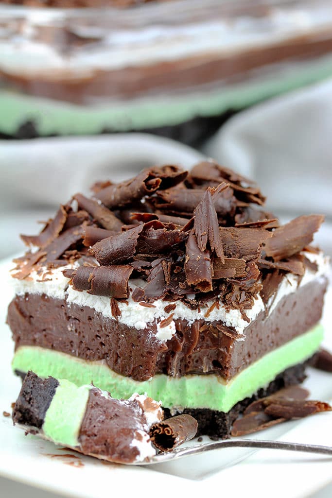 Mint Chocolate Lasagna easy no-bake dessert with layers of Oreo crust, mint cream cheese, chocolate pudding, Whipping Cream and Chocolate Curls on top.