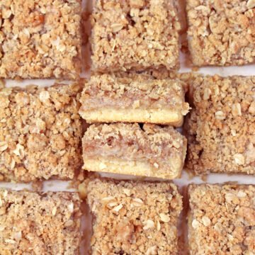 Overhead view of homemade Apple Crisp Bars cut into squares on parchment paper.