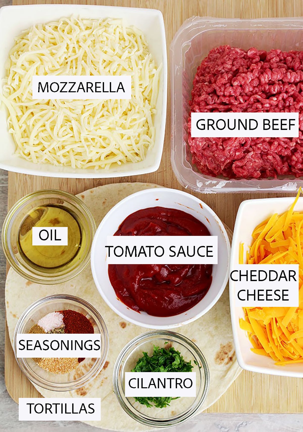 Ingredients for ground beef quesadillas, including ground beef, flour tortillas, cheddar and mozzarella cheese, tomato sauce, and seasonings.