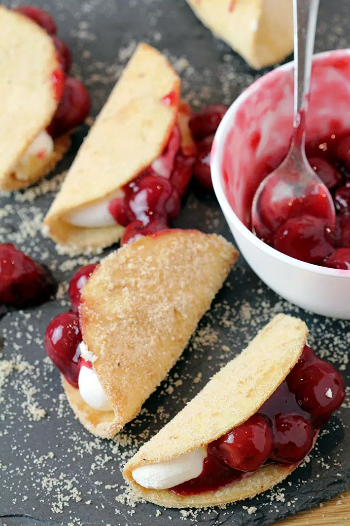 Cherry Cheesecake Tacos – these mini dessert tacos made with sweet ingredients and shaped like traditional tacos are so much fun to prepare, they look classy and are very delicious. You will love crunchy tortilla shells covered with sugar and cinnamon, filled with creamy no bake cheesecake filling that are topped with cherry pie filling.