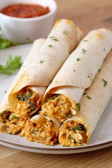 Cream Cheese Chicken Flautas - crunchy tortillas, juicy chicken and melted cheese make an incredible combination. These flautas are made of shredded cooked chicken, cream cheese, cheddar cheese, sour cream, spinach, salsa and different spices, all rolled up in tortillas, then baked or fried and finally served with salsa, guacamole sauce or sour cream