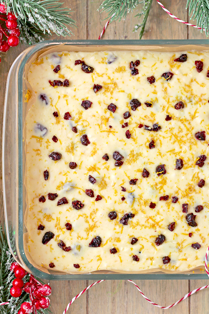 Pour the mixture into the already prepared pan and spread evenly. Sprinkle with cranberries and orange peel. Leave in the refrigerator for 6 hours or overnight. Cut into cubes before serving.