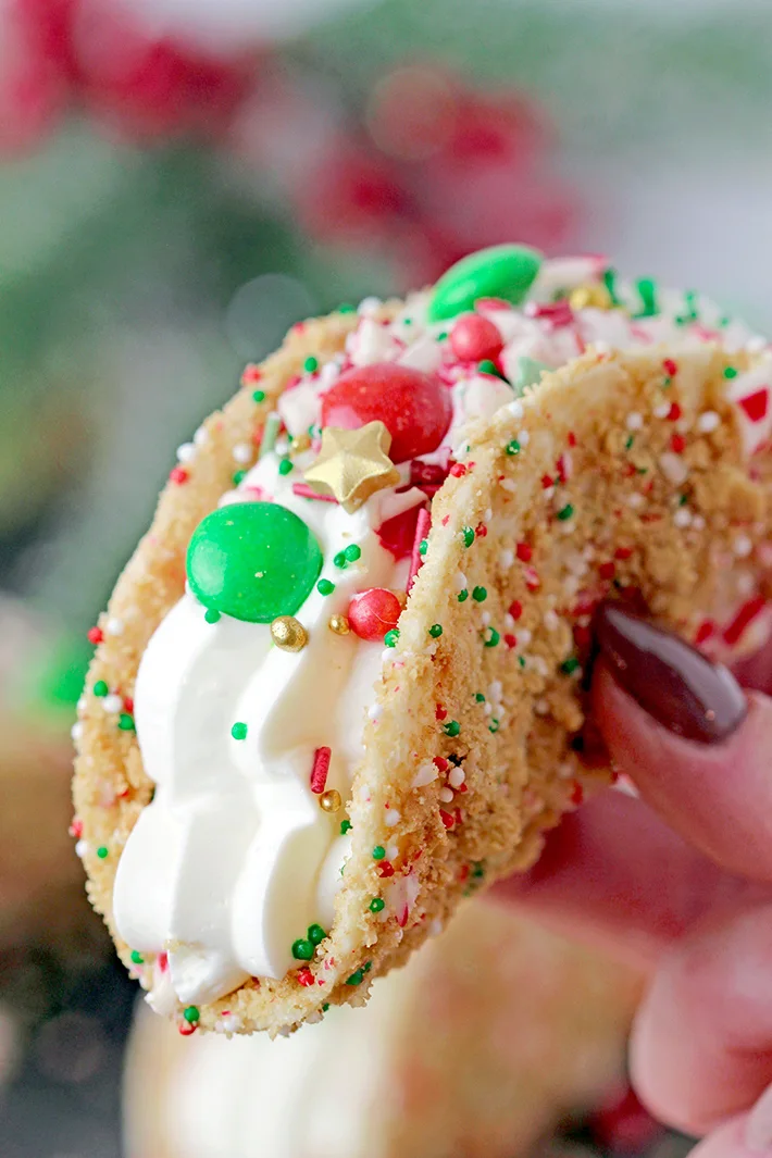 These Christmas Cheesecake Tacos with crunchy graham cracker tortilla shells, rich and creamy cheesecake filling, sprinkled with Christmas sprinkles, M&M's and crushed candy canes is an ultimate dessert you have to try for Christmas 2023! 