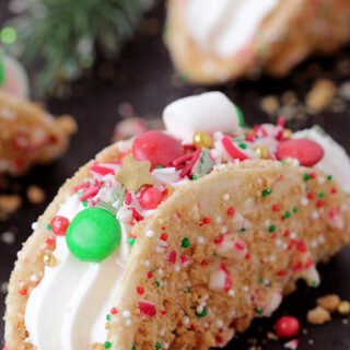 These Christmas Cheesecake Tacos with crunchy graham cracker tortilla shells, rich and creamy cheesecake filling, sprinkled with Christmas sprinkles, M&M's and crushed candy canes is an ultimate dessert you have to try for Christmas 2023! 
