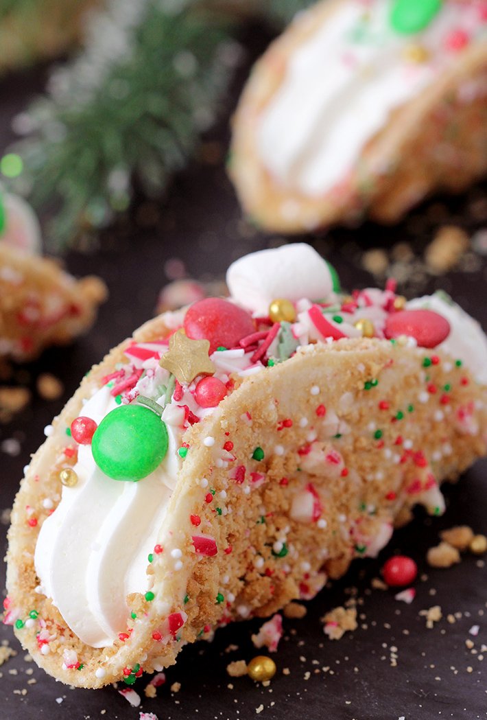 These Christmas Cheesecake Tacos with crunchy graham cracker tortilla shells, rich and creamy cheesecake filling, sprinkled with Christmas sprinkles, M&M's and crushed candy canes is an ultimate dessert you have to try for Christmas 2023! 