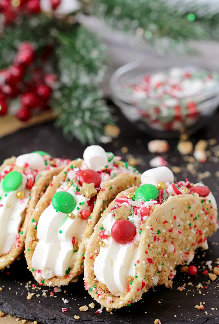 These Christmas Cheesecake Tacos with crunchy graham cracker tortilla shells, rich and creamy cheesecake filling, sprinkled with Christmas sprinkles, M&M's and crushed candy canes is an ultimate dessert you have to try for Christmas 2023! 