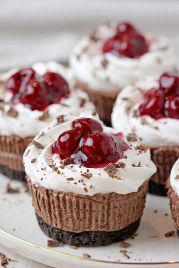 Black Forest Mini Cheesecakes – this easy no bake recipe with Oreo crust, decadent smooth chocolate cheesecake, juicy cherries on a soft, fluffy whipped cream cloud is a dessert you simply have to try.