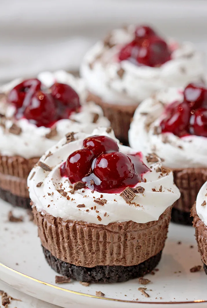 Black Forest Mini Cheesecakes – this easy no bake recipe with Oreo crust, decadent smooth chocolate cheesecake, juicy cherries on a soft, fluffy whipped cream cloud is a dessert you simply have to try.