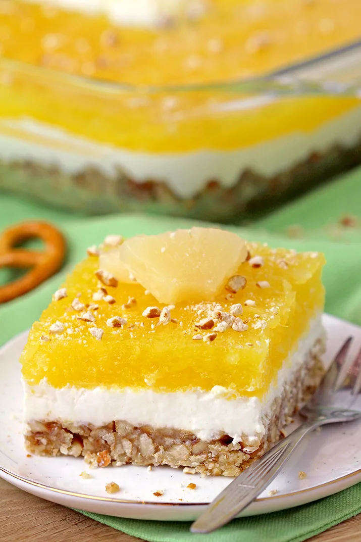 Pineapple Pretzel Salad - with crunchy pretzel crust, creamy filling made of cream cheese and cool whip, with refreshing pineapple layer on top is easy to prepare and so tasty. The combination of sweet and salty, crunchy and creamy and tropical taste best describe this unique salad, perfect for potlucks or holidays.