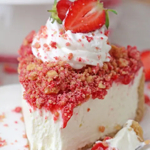 Strawberry Crunch Cheesecake - prepare this easy, no-bake recipe for BBQs, holidays or parties and it’ll  be a huge hit!!! Graham cracker crust, creamy, smooth cheesecake filling, strawberry sauce and  strawberry crunch topping with whipped topping and fresh strawberries on top make this delicious dessert.