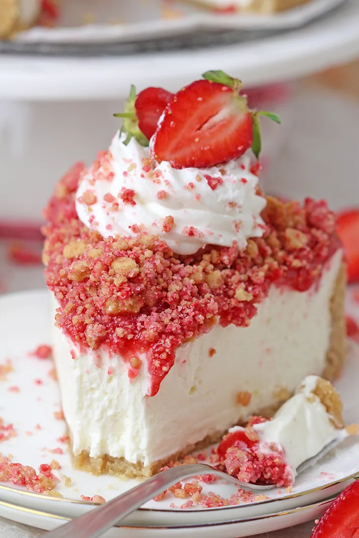 Strawberry Crunch Cheesecake - prepare this easy, no-bake recipe for BBQs, holidays or parties and it’ll  be a huge hit!!! Graham cracker crust, creamy, smooth cheesecake filling, strawberry sauce and  strawberry crunch topping with whipped topping and fresh strawberries on top make this delicious dessert.