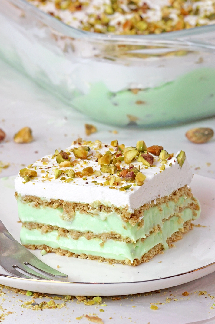 This Pistachio Icebox Cake is a super quick and easy recipe made with layers of graham crackers, instant pistachio pudding filling, and whipped topping in between. It’s topped with whipped topping and chopped pistachios. Made with just 5 simple ingredients in only 10 minutes, it’s perfect when you don’t have much time but want a delicious treat!
