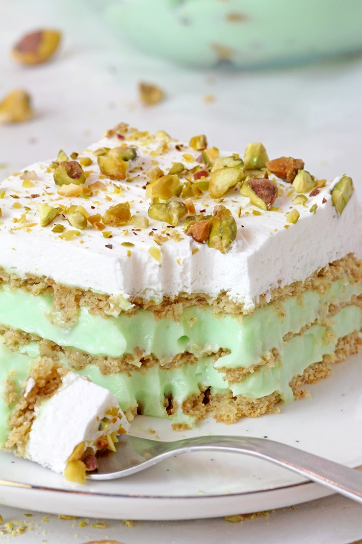 This Pistachio Icebox Cake is a super quick and easy recipe made with layers of graham crackers, instant pistachio pudding filling, and whipped topping in between. It’s topped with whipped topping and chopped pistachios. Made with just 5 simple ingredients in only 10 minutes, it’s perfect when you don’t have much time but want a delicious treat!