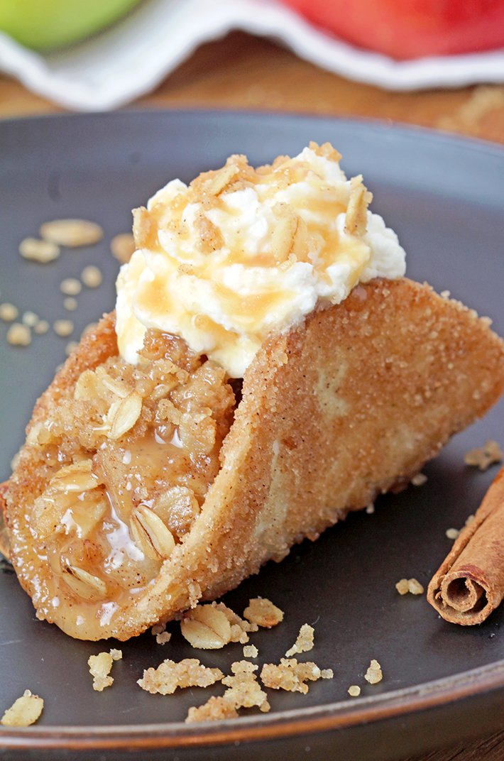 These Apple Crisp Tacos are the ultimate fall dessert, made with crispy cinnamon - sugar tortilla shells filled with apple crisp, topped with whipped topping or ice cream and drizzled with caramel sauce. They are perfect for gatherings, parties, picnics or even holidays.