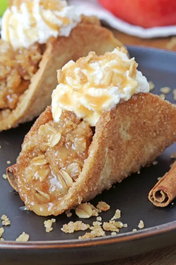 These Apple Crisp Tacos are the ultimate fall dessert, made with crispy cinnamon - sugar tortilla shells filled with apple crisp, topped with whipped topping or ice cream and drizzled with caramel sauce. They are perfect for gatherings, parties, picnics or even holidays.