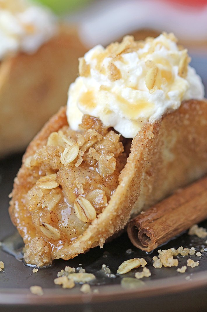 These Apple Crisp Tacos are the ultimate fall dessert, made with crispy cinnamon - sugar tortilla shells filled with apple crisp, topped with whipped topping or ice cream and drizzled with caramel sauce. They are perfect for gatherings, parties, picnics or even holidays.