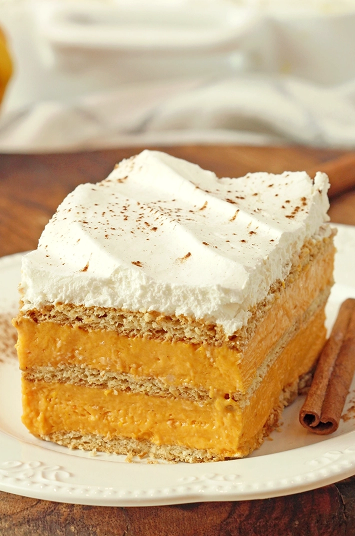 No-Bake Pumpkin Eclair Cake with layers of graham crackers and creamy pumpkin filling, topped with whipped topping, an easy Thanksgiving dessert