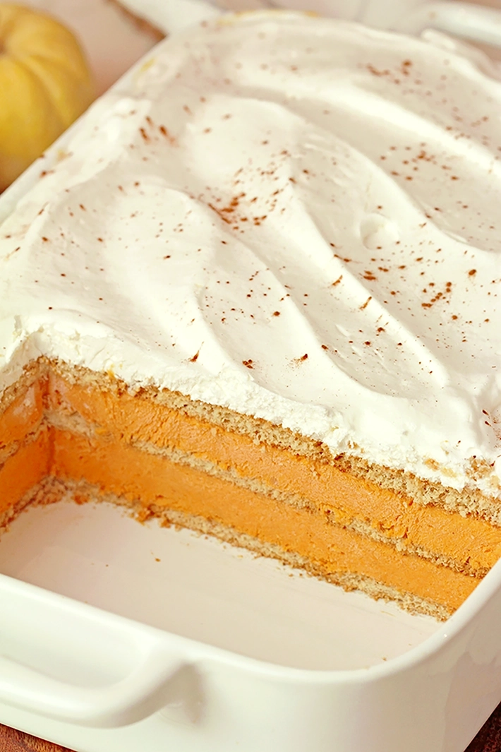 No-Bake Pumpkin Eclair Cake with layers of graham crackers and creamy pumpkin filling, topped with whipped topping, an easy Thanksgiving dessert