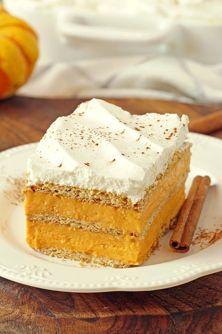 No-Bake Pumpkin Eclair Cake with layers of graham crackers and creamy pumpkin filling, topped with whipped topping, an easy Thanksgiving dessert