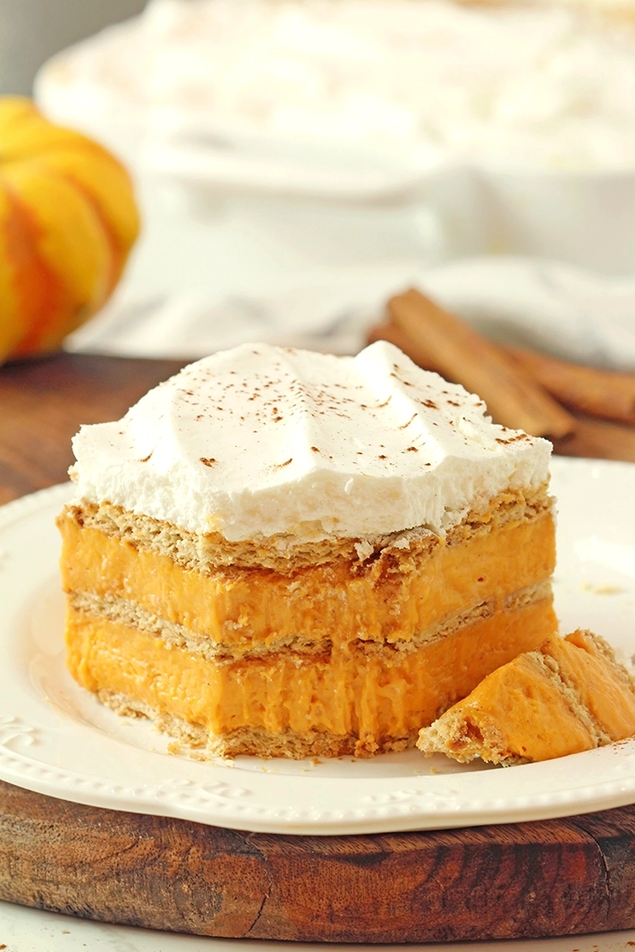 No-Bake Pumpkin Eclair Cake with layers of graham crackers and creamy pumpkin filling, topped with whipped topping, an easy Thanksgiving dessert