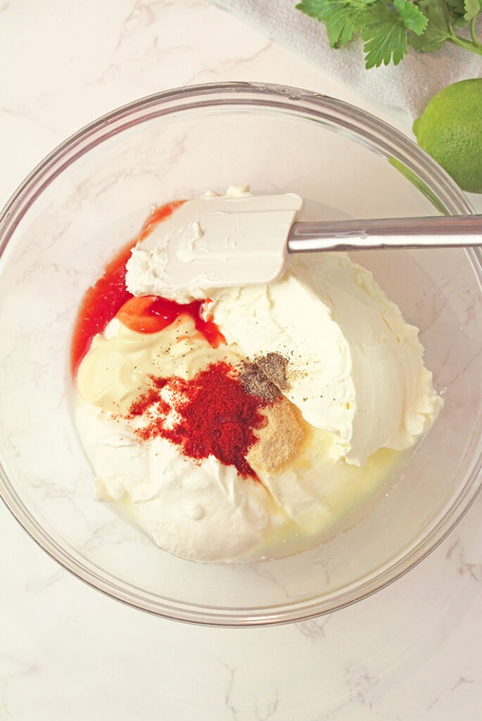 Fold in corn, jalapeño, ½ cup shredded cheddar, cotija or feta cheese, green onions, and cilantro.