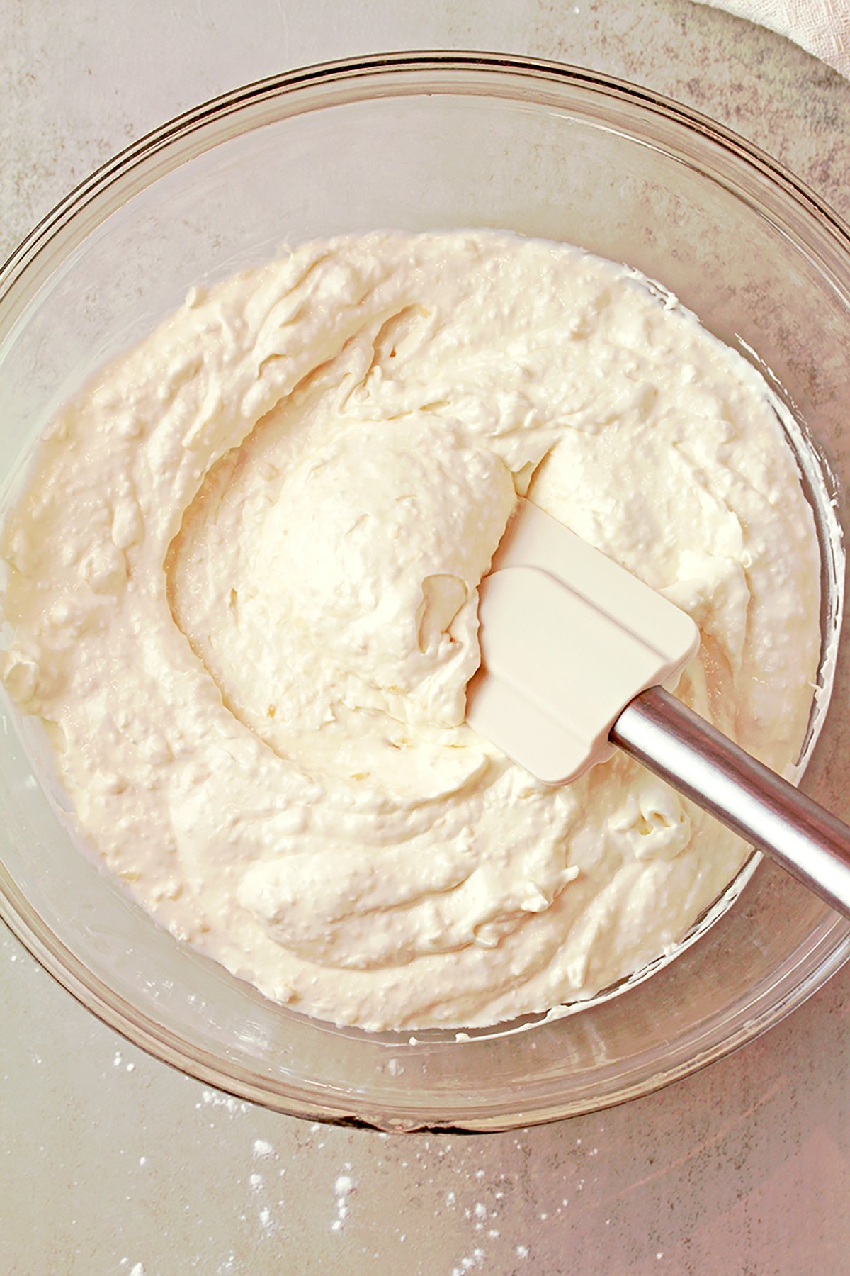 Coconut pineapple cream cheese frosting in a bowl, light and fluffy texture.