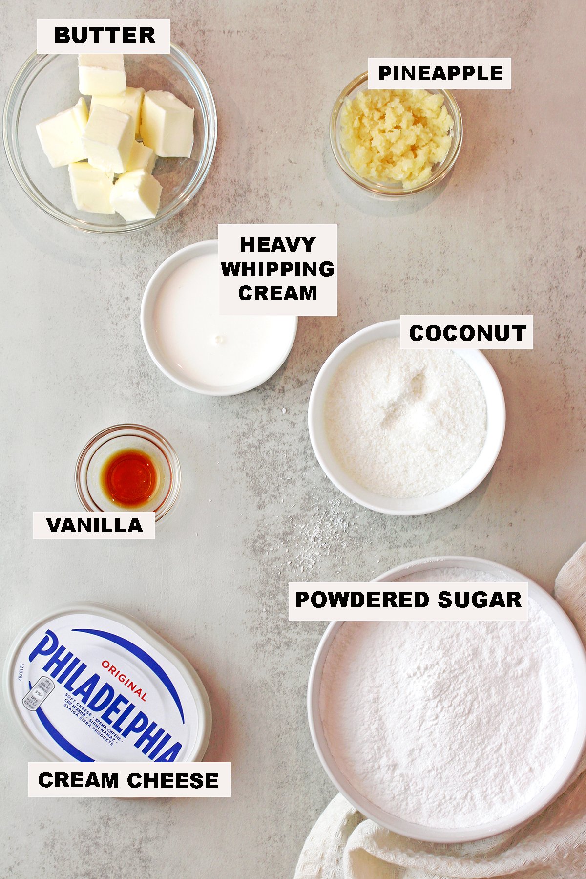 Ingredients for coconut pineapple cream cheese frosting including cream cheese, butter, powdered sugar, pineapple, coconut, vanilla, and cream.