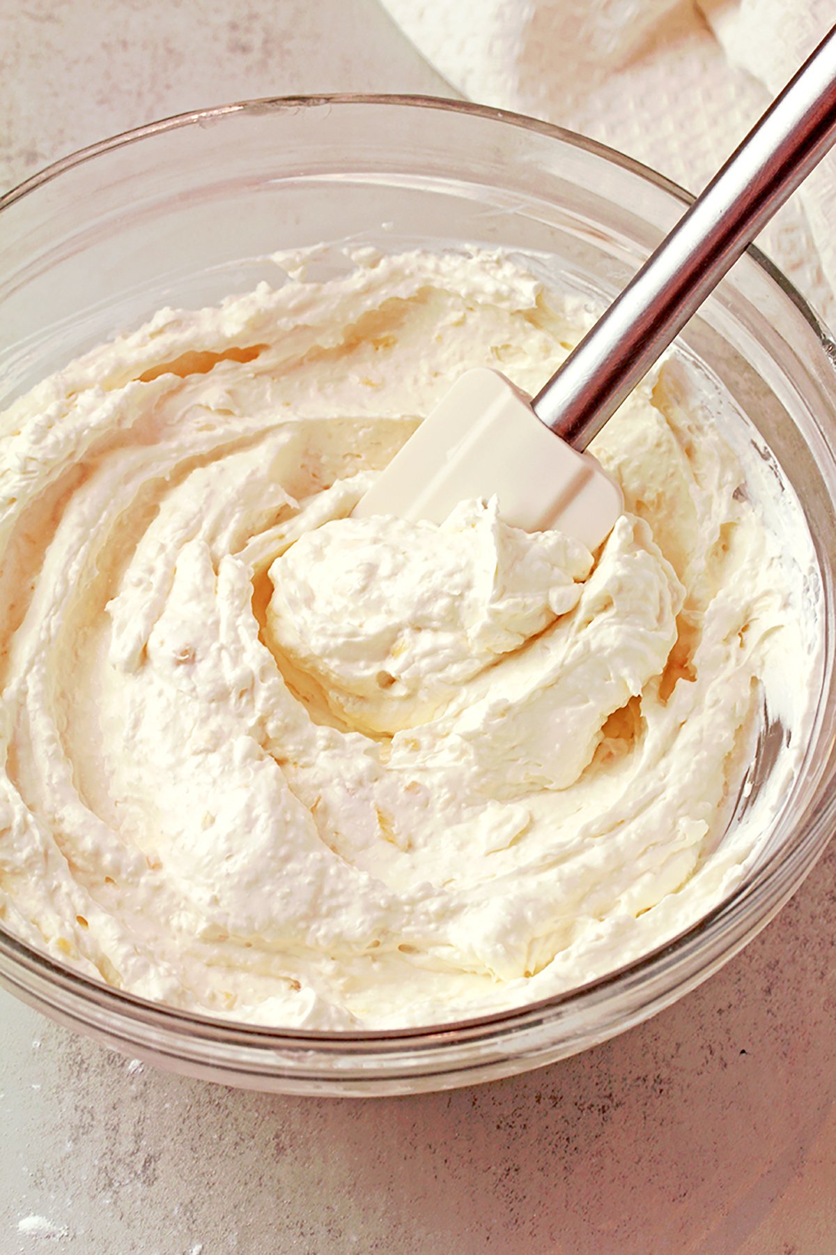 Coconut pineapple cream cheese frosting in a bowl, light and fluffy texture.