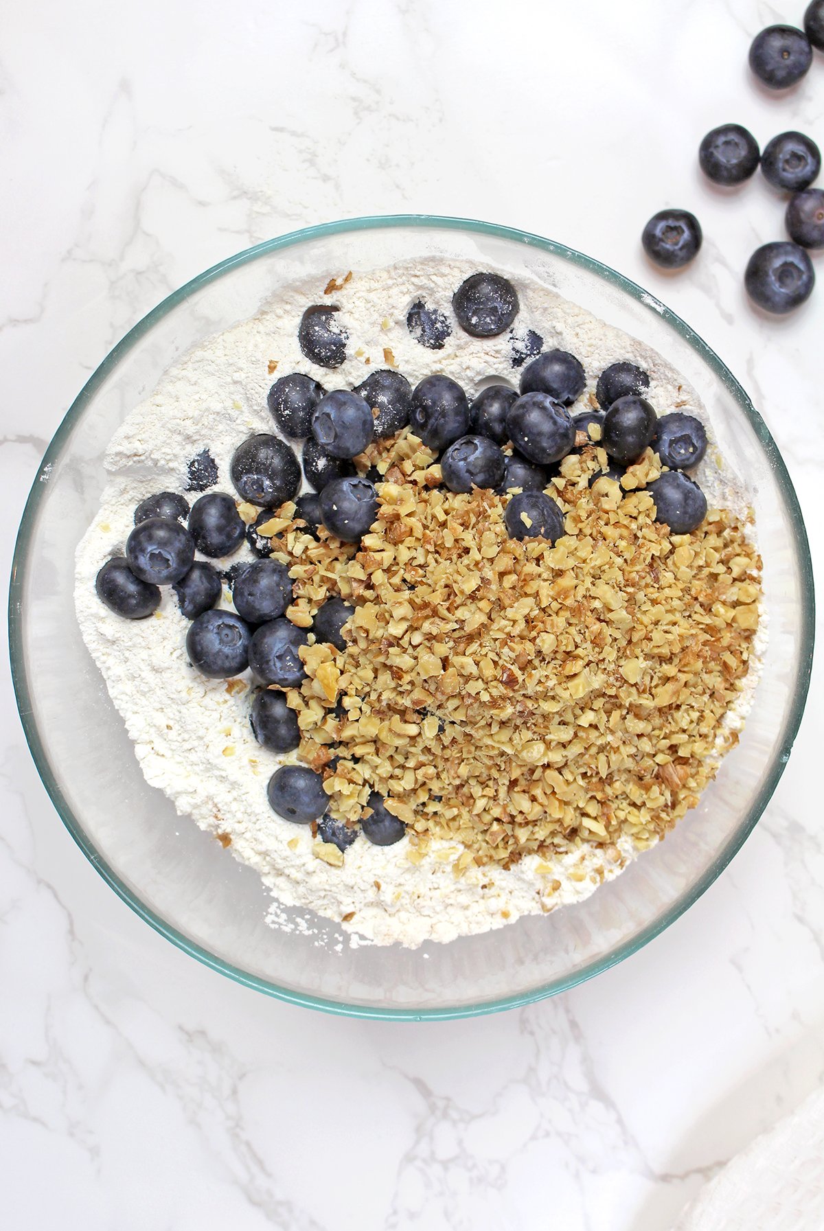 Step 3. Add the Blueberries and Walnuts
Stir the blueberries and chopped walnuts into the dry ingredients. Coating them with flour helps keep them evenly distributed throughout the batter.