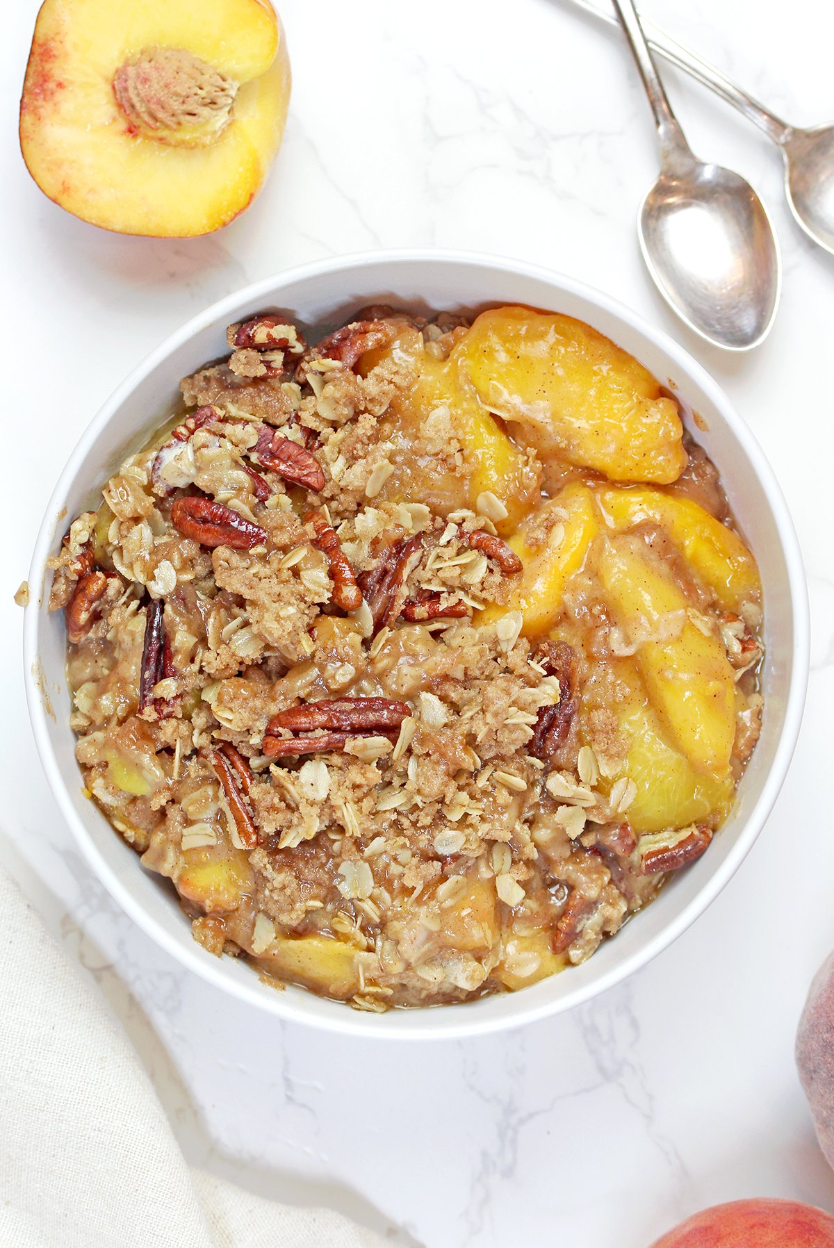 Freshly baked Peach Crisp cooling in a baking dish before serving, with a golden buttery oat crumble topping.