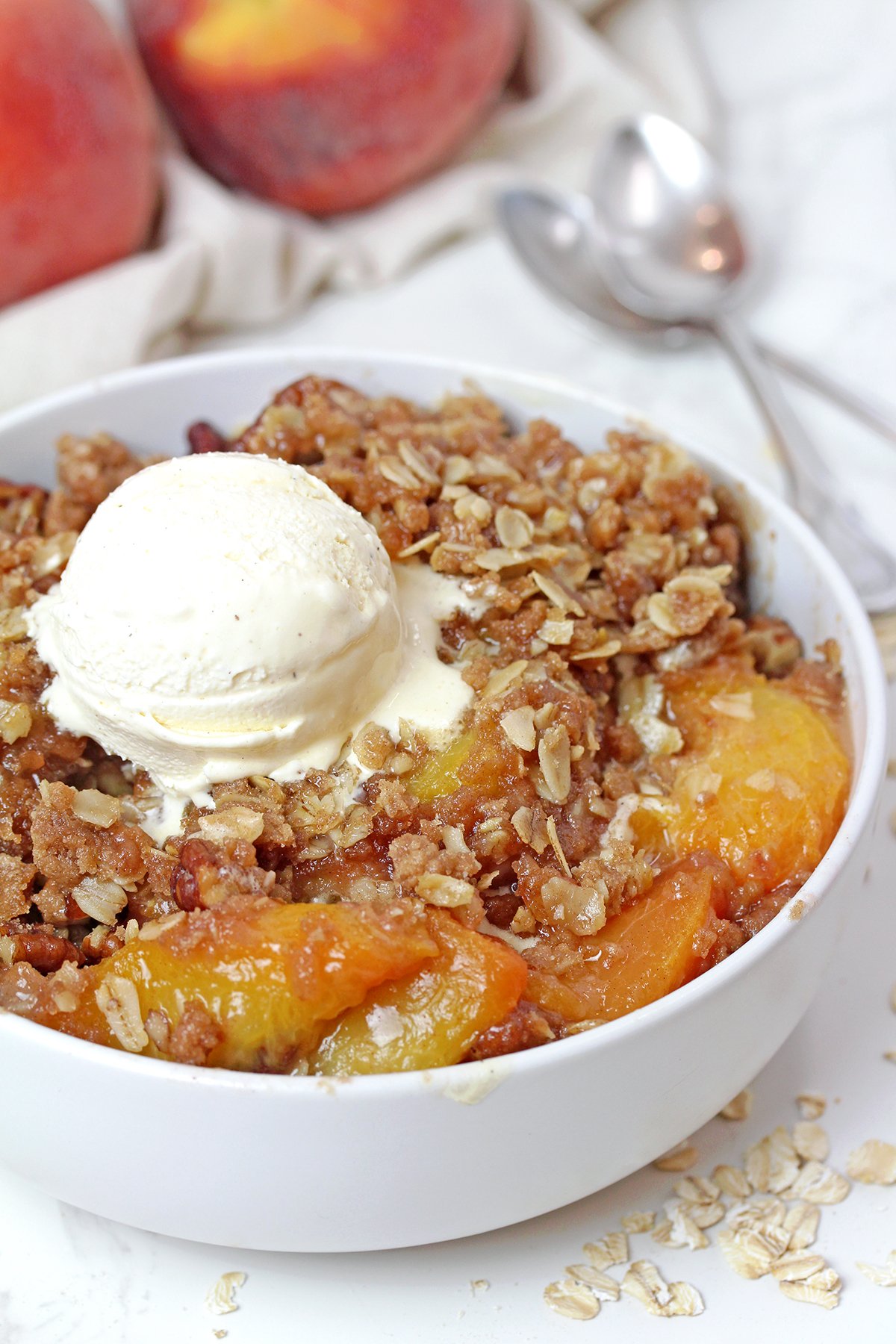 Homemade Peach Crisp served warm with melting vanilla ice cream.