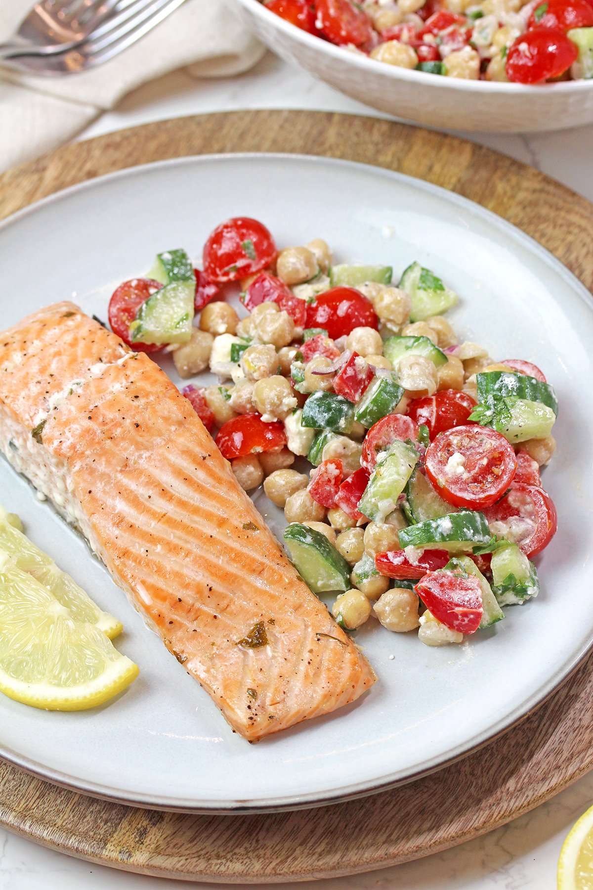 Mediterranean chickpea salad with grilled salmon, fresh vegetables, feta cheese, and lemon dressing.
