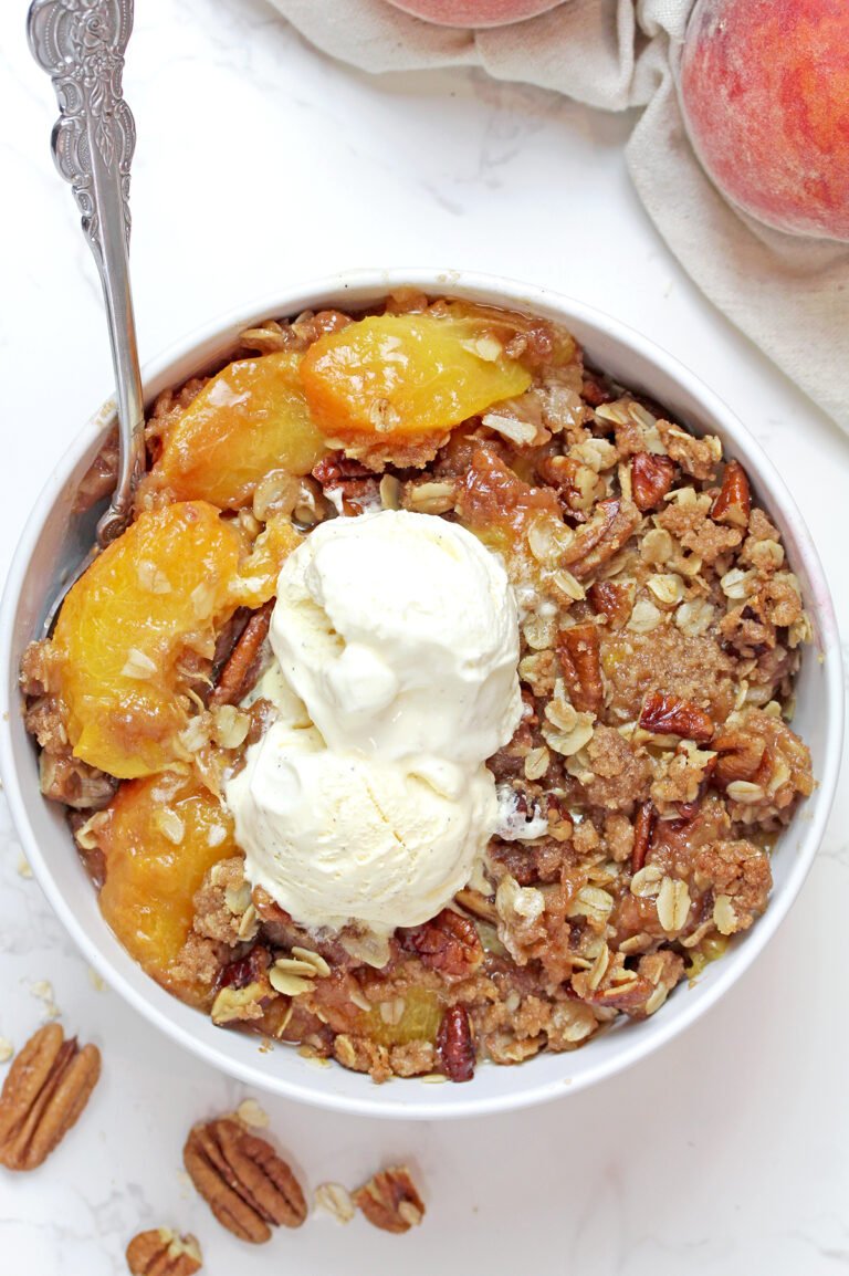 Serving homemade Peach Crisp with a scoop of vanilla ice cream.
