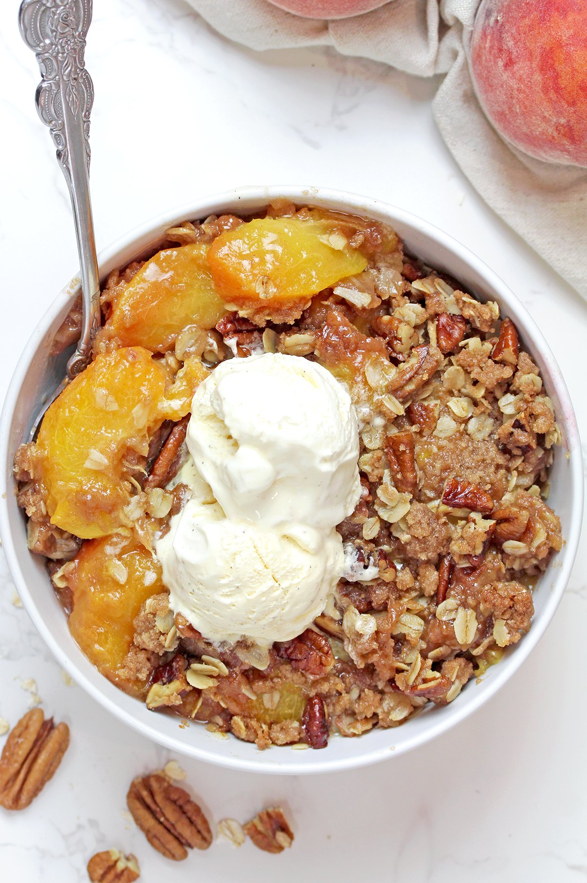 Summer dessert with juicy fresh peaches and a buttery oat crumble topping served with vanilla ice cream.