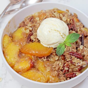 Warm homemade Peach Crisp served with a scoop of creamy vanilla ice cream