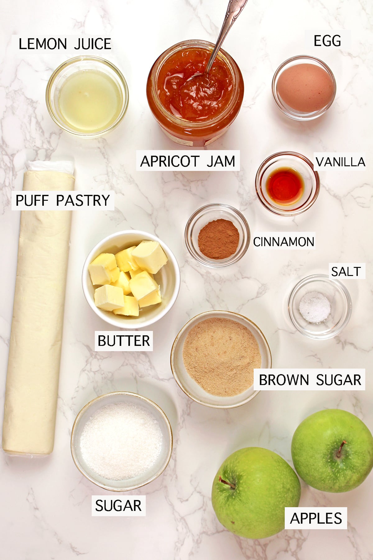 Ingredients for easy puff pastry apple tart with apples, puff pastry, apricot jam, cinnamon sugar, butter and lemon.