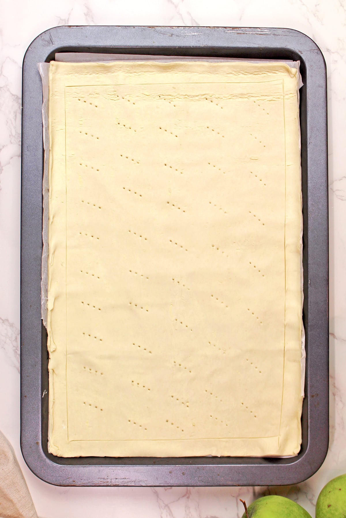 Preparing puff pastry for an easy puff pastry apple tart, rolled out and scored around the edges.