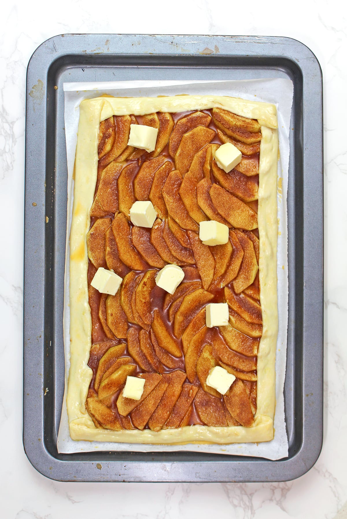 Brushing puff pastry edges with egg wash and adding butter to the apples for an apple tart.