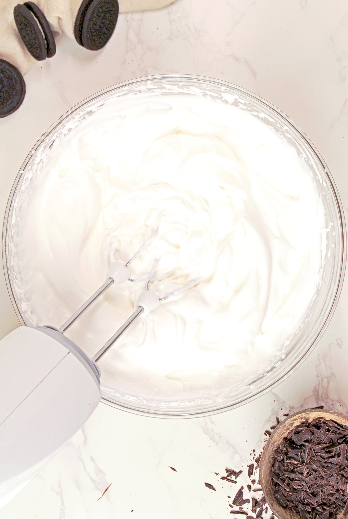 Whipping heavy cream with powdered sugar and vanilla extract until soft peaks form for the Mississippi Mud Pie topping.