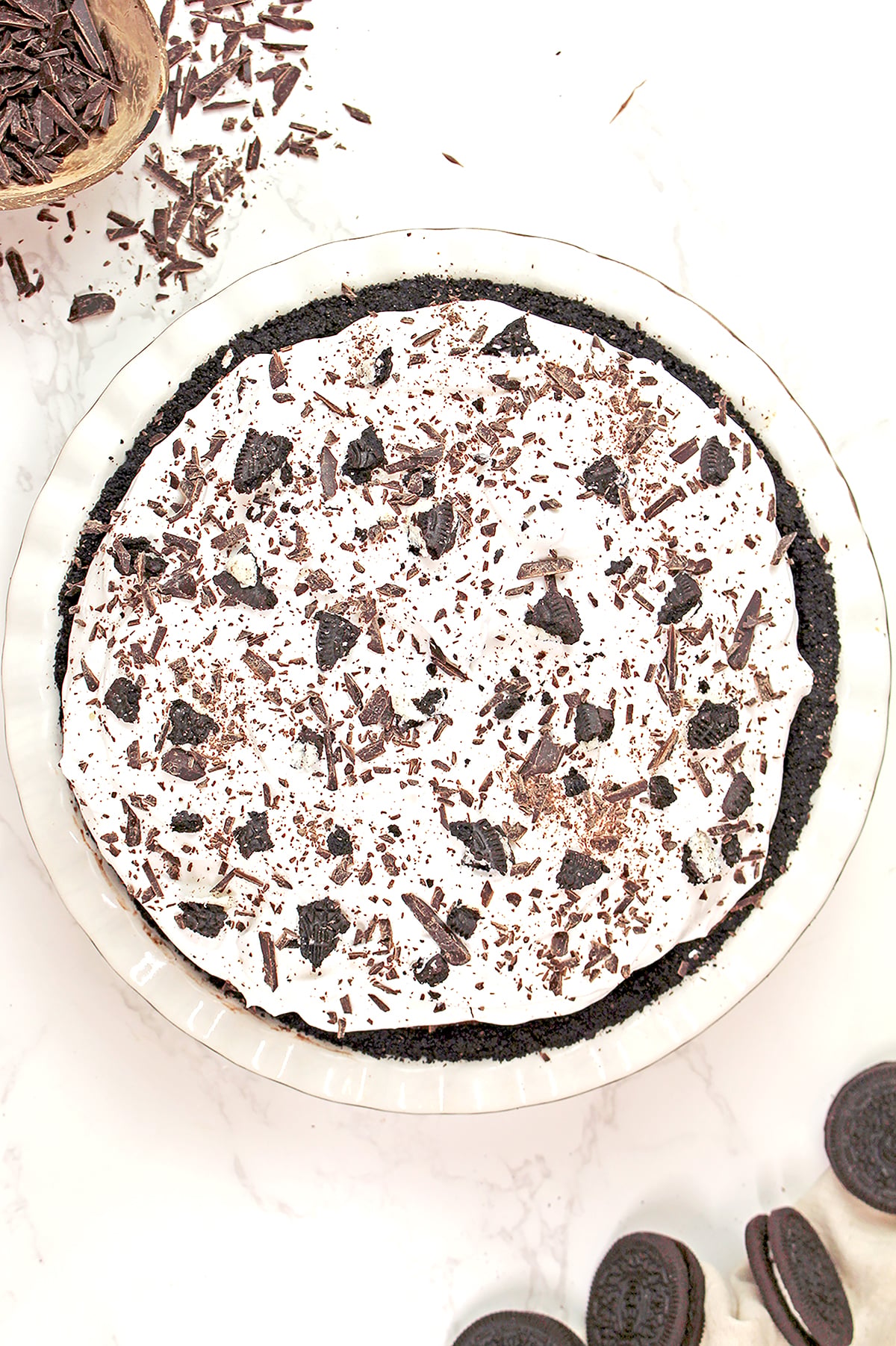 Mississippi Mud Pie topped with fluffy whipped cream and crushed Oreo cookies, showing rich chocolate brownie and pudding layers on an Oreo crust.