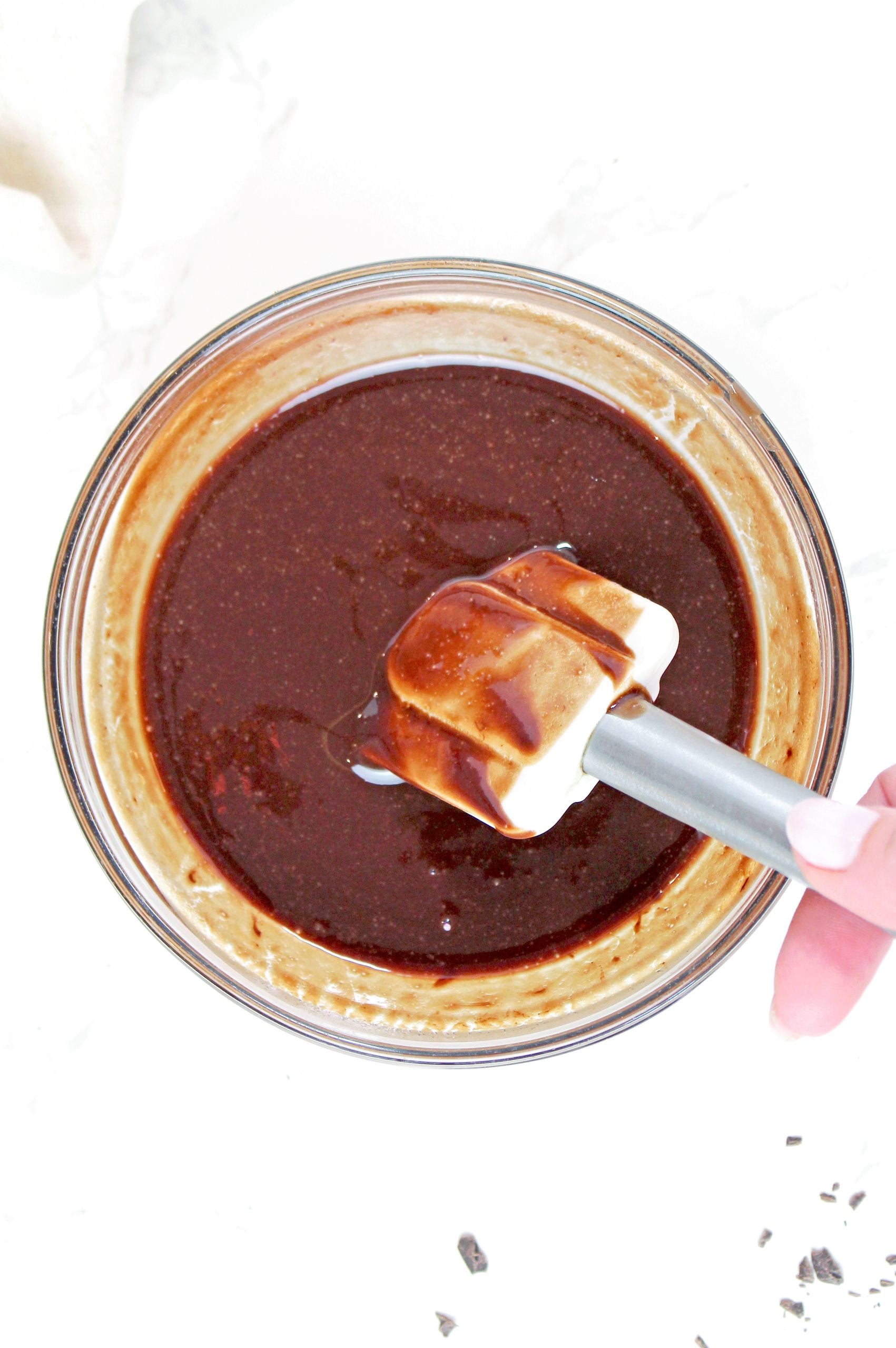 Chopped chocolate stirred into melted butter until smooth to prepare the brownie layer for Mississippi Mud Pie.